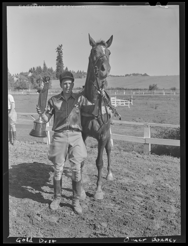 1940-06-15 Hunt Club - Omer Bonney stands next to his horse (Gold Dust) while holding a trophy, during the spring race meet for the Portland Hunt Club in Garden Home